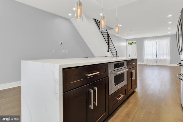 kitchen with pendant lighting, light hardwood / wood-style flooring, oven, and a kitchen island