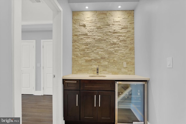 bar with sink, dark hardwood / wood-style floors, tasteful backsplash, dark brown cabinets, and beverage cooler