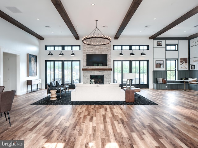 unfurnished living room featuring french doors, a brick fireplace, an inviting chandelier, and light hardwood / wood-style floors