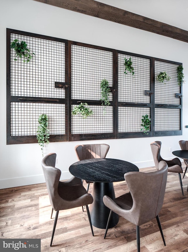 dining area featuring beam ceiling, a healthy amount of sunlight, and hardwood / wood-style flooring