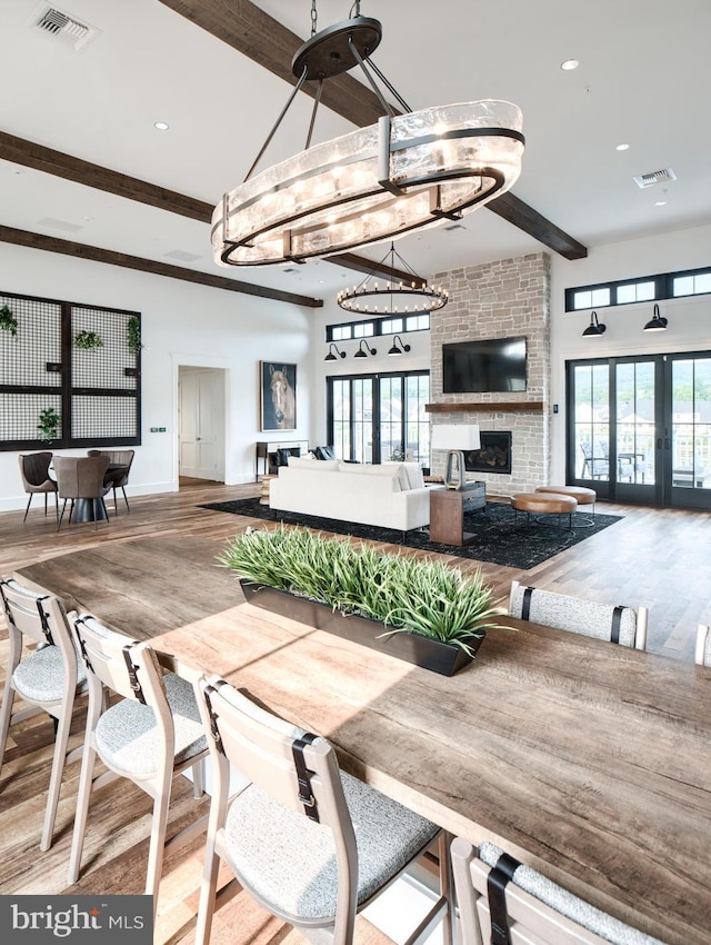 dining area featuring french doors, beam ceiling, a fireplace, and plenty of natural light