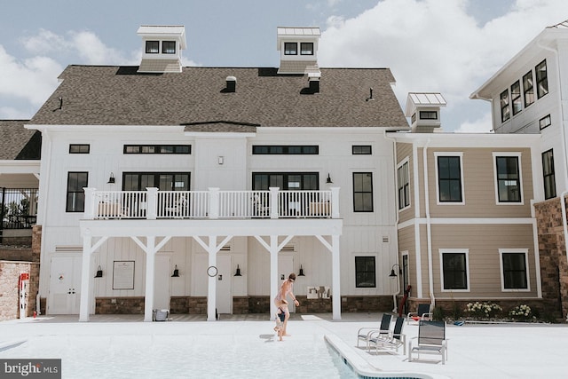 back of property featuring a swimming pool and a balcony