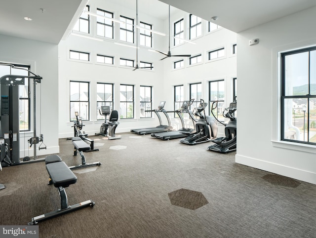 workout area featuring dark colored carpet and a towering ceiling