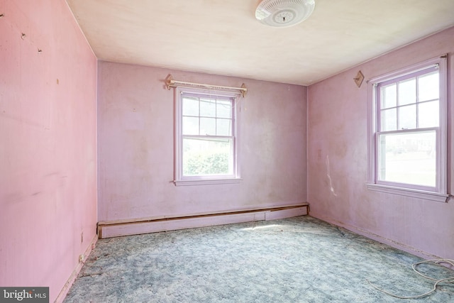 carpeted spare room with a baseboard heating unit