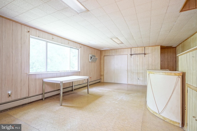 interior space with a baseboard heating unit and wood walls