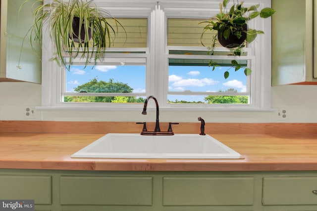 interior details featuring butcher block counters, sink, and green cabinetry