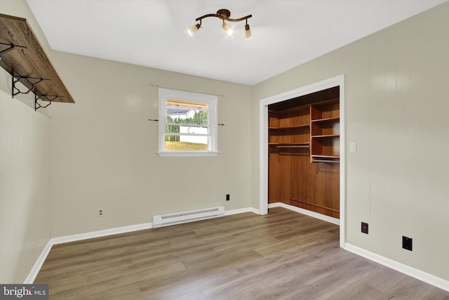 unfurnished bedroom featuring baseboard heating, a closet, and light wood-type flooring