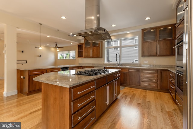 kitchen with sink, island exhaust hood, a center island, stainless steel appliances, and light wood-type flooring