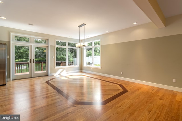 empty room with french doors, beam ceiling, a chandelier, and light wood-type flooring