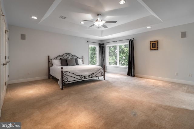 carpeted bedroom with ceiling fan and a raised ceiling