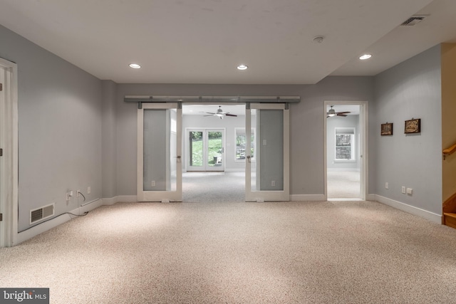 empty room with a barn door, carpet flooring, and ceiling fan