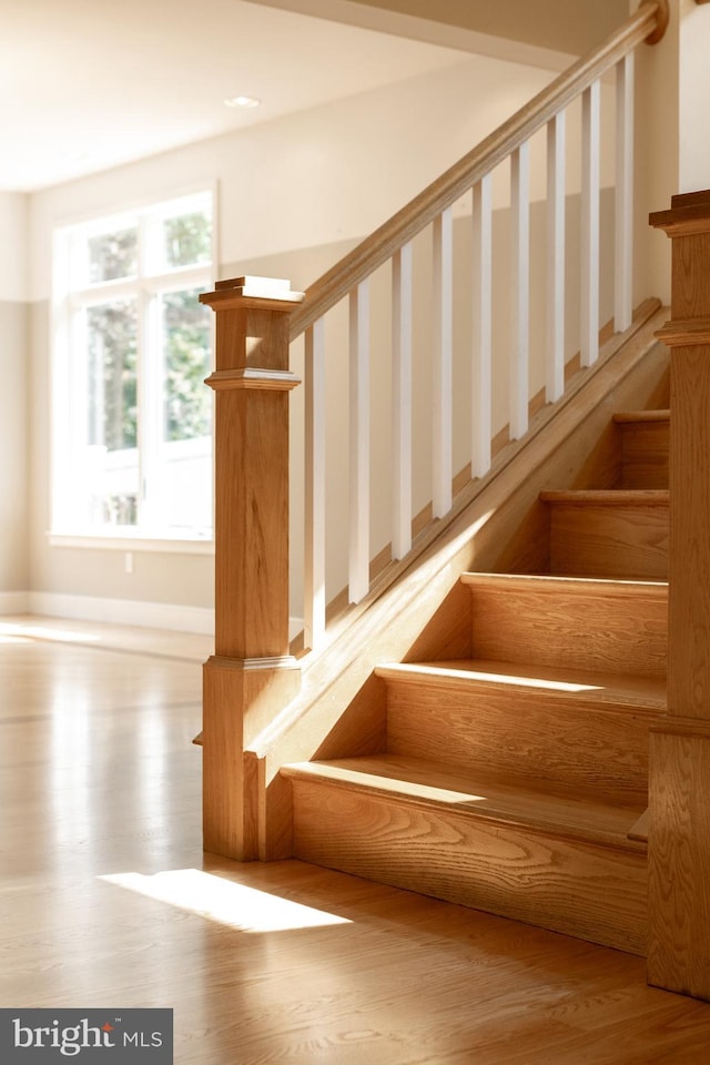 stairway featuring a healthy amount of sunlight and hardwood / wood-style floors