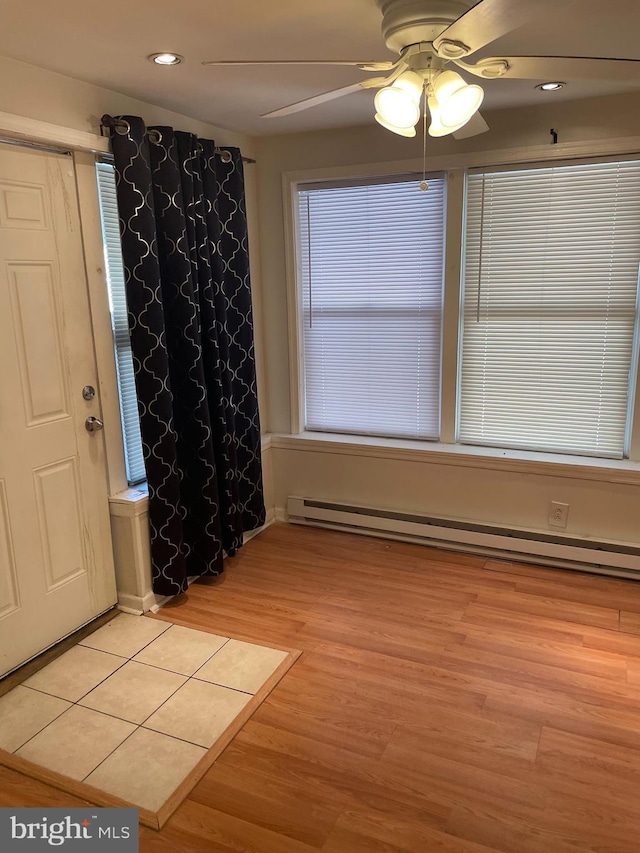 interior space with a baseboard radiator, ceiling fan, and light hardwood / wood-style floors