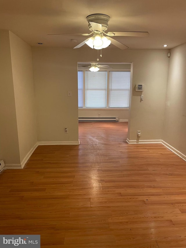 unfurnished room featuring baseboard heating, ceiling fan, and wood-type flooring