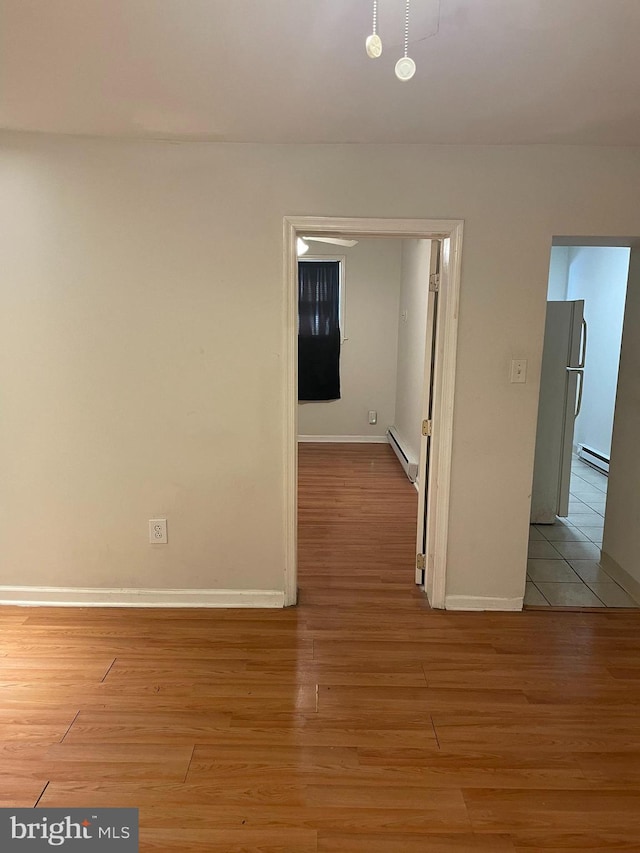 spare room featuring light wood-type flooring and a baseboard radiator