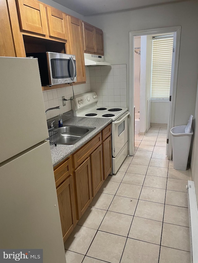 kitchen featuring backsplash, sink, light tile patterned floors, and white appliances