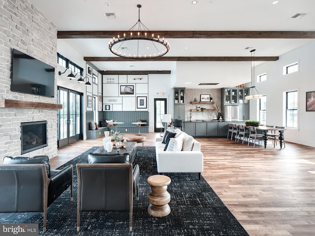 living room with beamed ceiling, plenty of natural light, a stone fireplace, and wood-type flooring