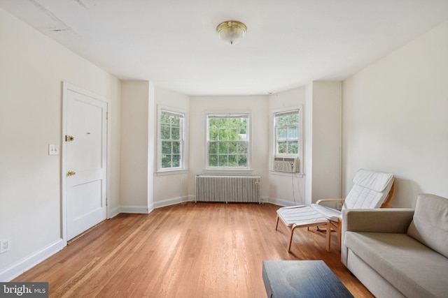 living area with radiator heating unit, light wood-type flooring, and cooling unit