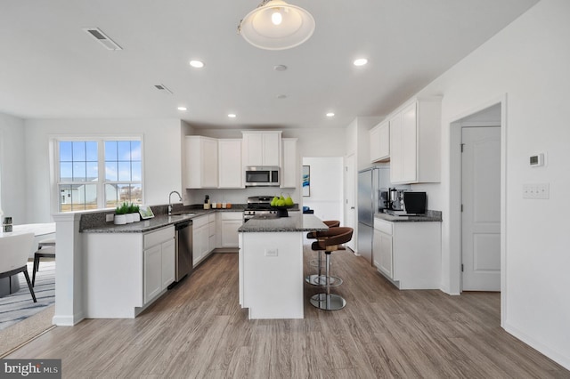 kitchen featuring white cabinets, stainless steel appliances, and light wood-type flooring