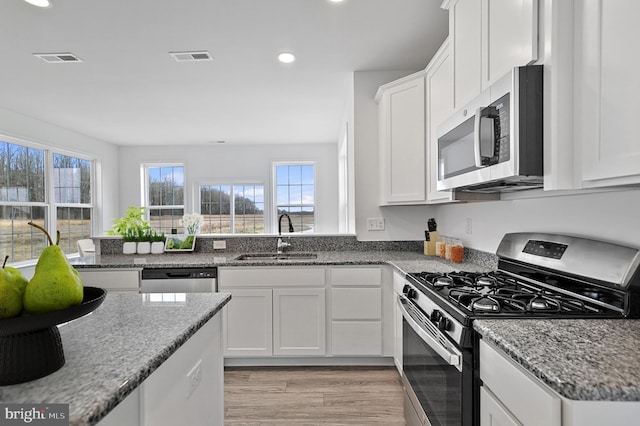 kitchen with stainless steel appliances, white cabinetry, a healthy amount of sunlight, and sink