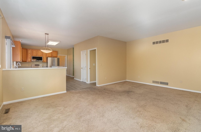 unfurnished living room featuring light colored carpet and sink