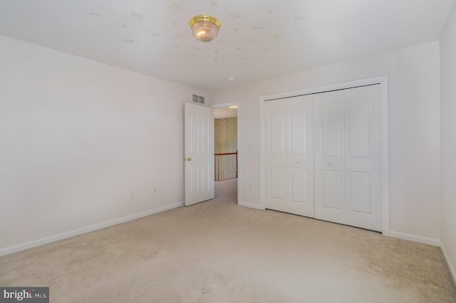 unfurnished bedroom featuring light carpet and a closet