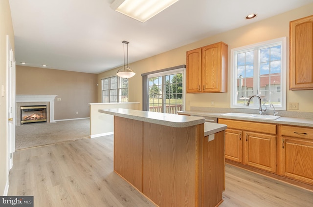 kitchen with light hardwood / wood-style flooring, hanging light fixtures, a kitchen island, and sink