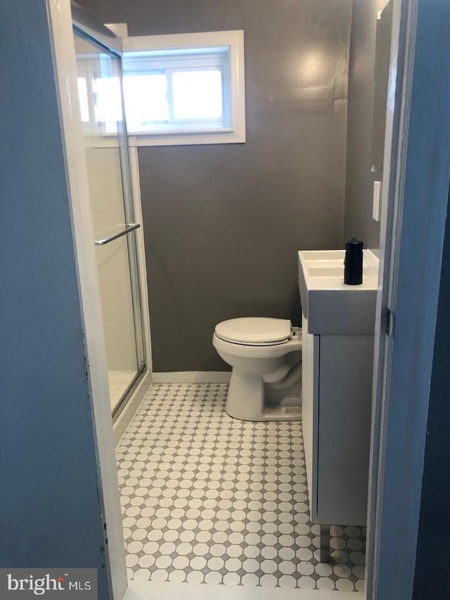 bathroom featuring vanity, toilet, and a shower with door