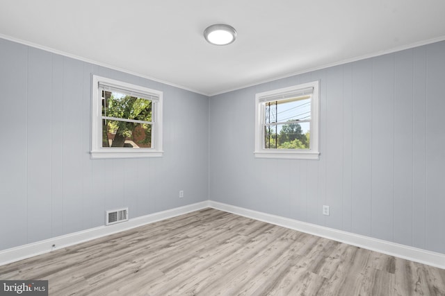 unfurnished room featuring plenty of natural light, light hardwood / wood-style flooring, and crown molding