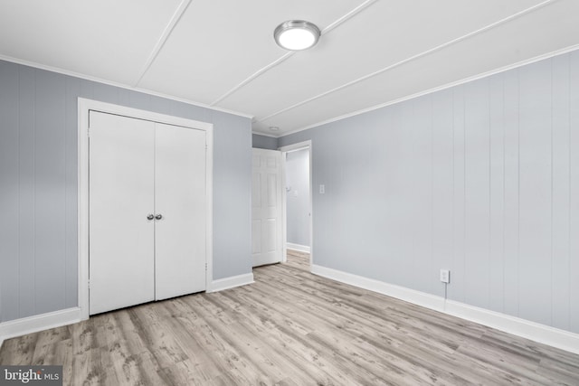 unfurnished bedroom featuring a closet, ornamental molding, and light hardwood / wood-style floors