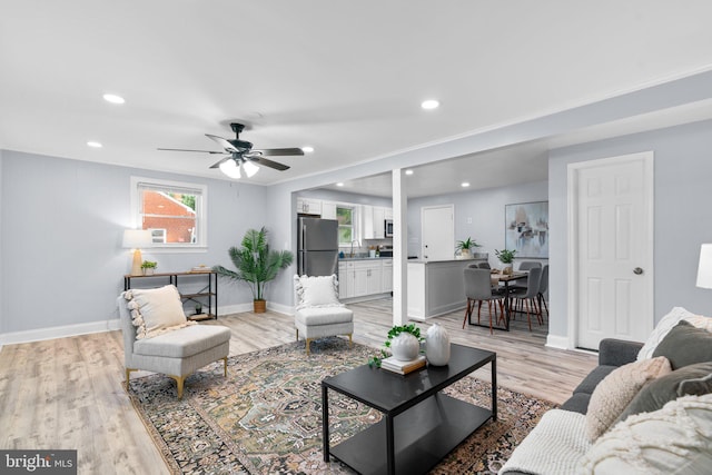 living room with ceiling fan, sink, and light wood-type flooring