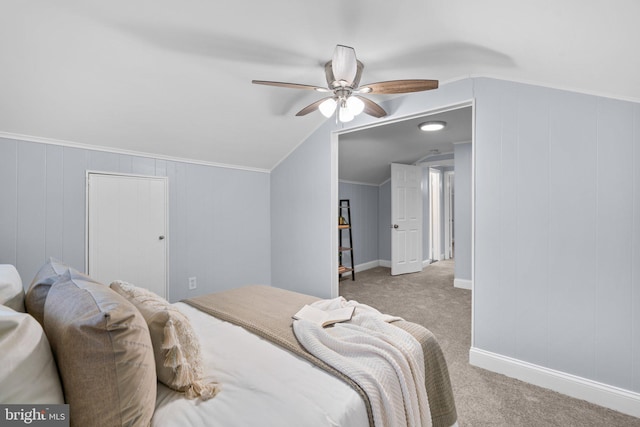 carpeted bedroom featuring ceiling fan, vaulted ceiling, and ornamental molding