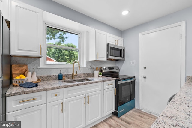 kitchen featuring decorative backsplash, sink, white cabinetry, stainless steel appliances, and light stone counters