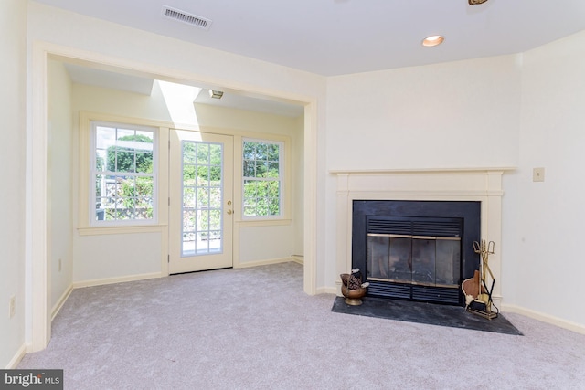 unfurnished living room featuring light colored carpet and plenty of natural light