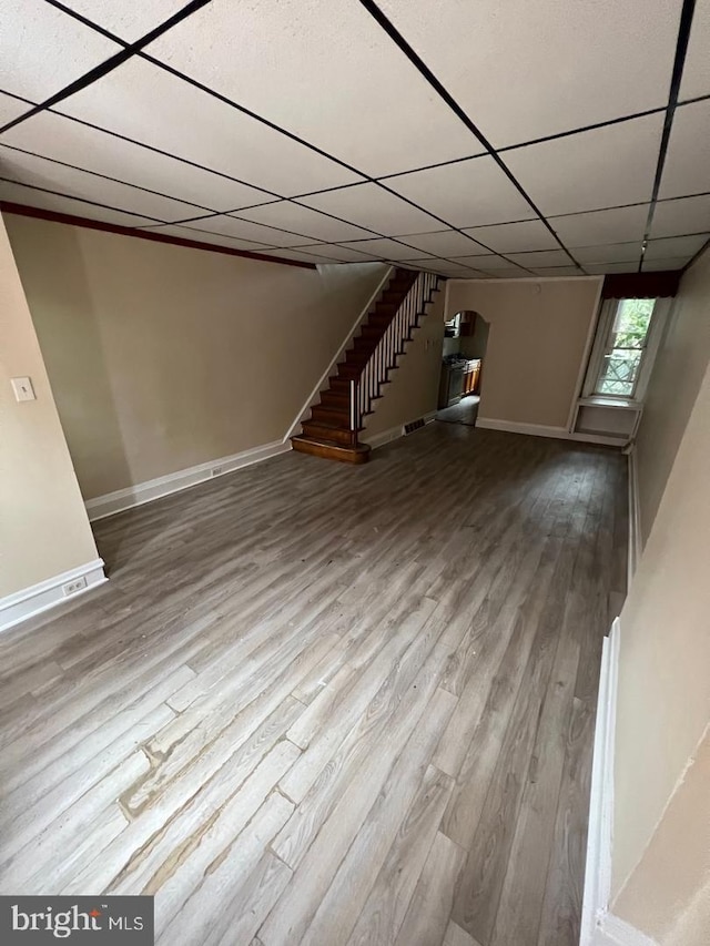 basement with a drop ceiling and hardwood / wood-style flooring