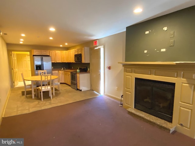 kitchen with light carpet, appliances with stainless steel finishes, and light brown cabinetry