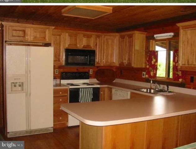 kitchen featuring kitchen peninsula, sink, dark hardwood / wood-style floors, and white appliances