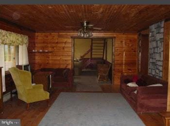 sitting room featuring rustic walls, ceiling fan, and wood ceiling