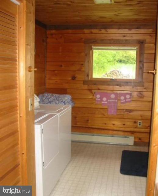 laundry area with separate washer and dryer and wood walls