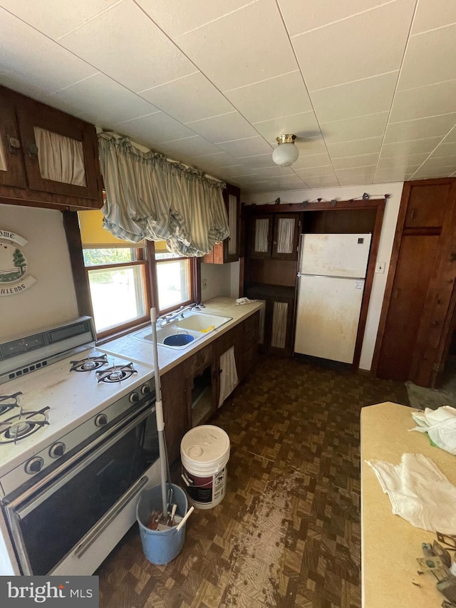 kitchen featuring dark parquet flooring, sink, and white appliances