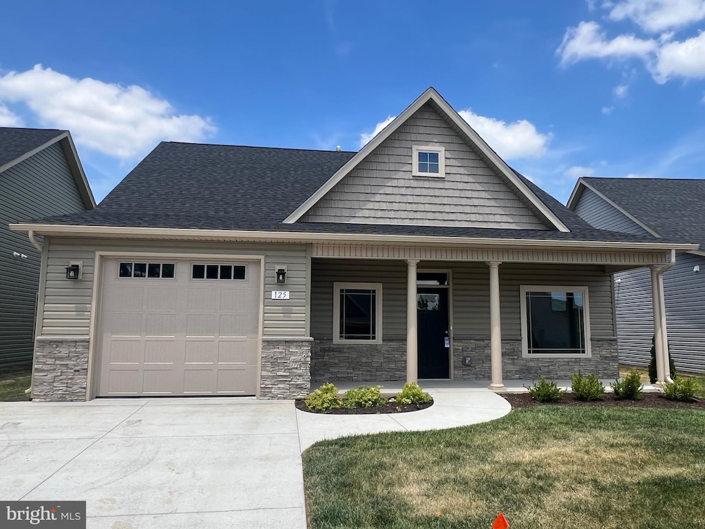 craftsman inspired home with a front yard, a porch, and a garage