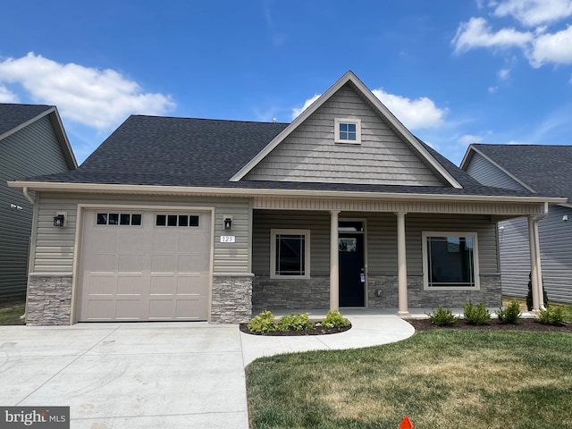 craftsman inspired home with a front yard, a porch, and a garage