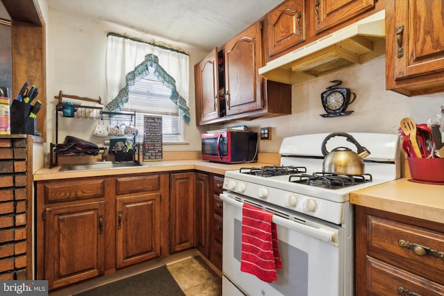 kitchen with sink, gas range gas stove, light tile patterned floors, and custom range hood