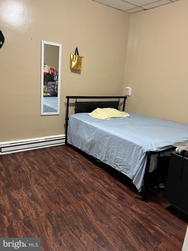 bedroom featuring a paneled ceiling, dark wood-type flooring, and a baseboard radiator