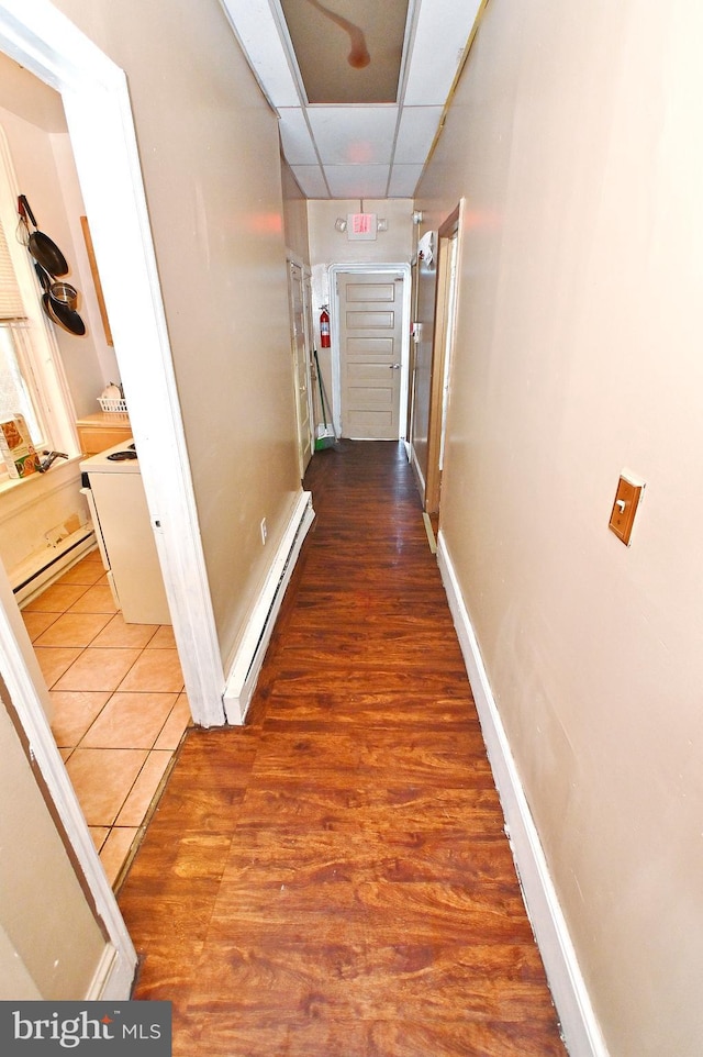 corridor featuring a drop ceiling, hardwood / wood-style flooring, and baseboard heating