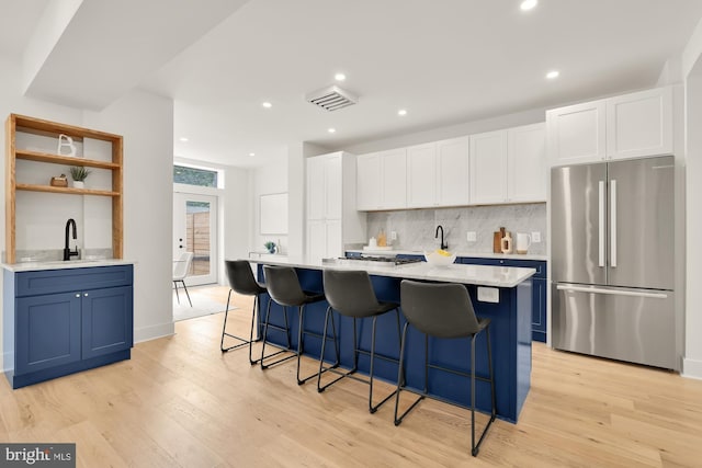 kitchen featuring a breakfast bar, a kitchen island, light hardwood / wood-style flooring, white cabinetry, and stainless steel refrigerator