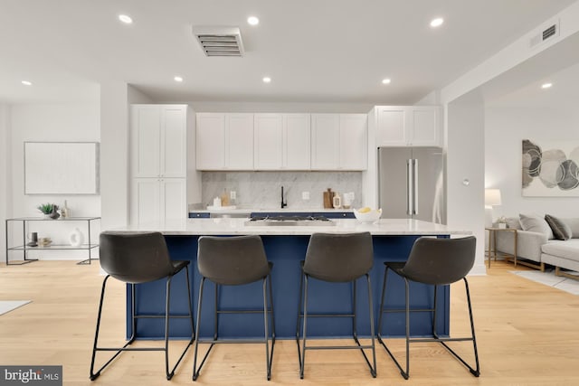 kitchen with high end refrigerator, white cabinetry, and a large island