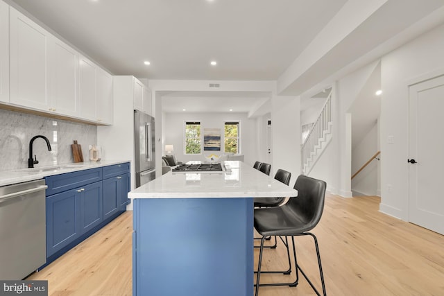 kitchen featuring a center island, white cabinets, a kitchen breakfast bar, appliances with stainless steel finishes, and tasteful backsplash