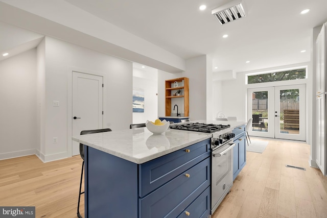 kitchen featuring stainless steel range, french doors, a kitchen breakfast bar, blue cabinets, and a kitchen island