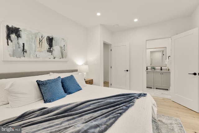 bedroom with light hardwood / wood-style floors and ensuite bath